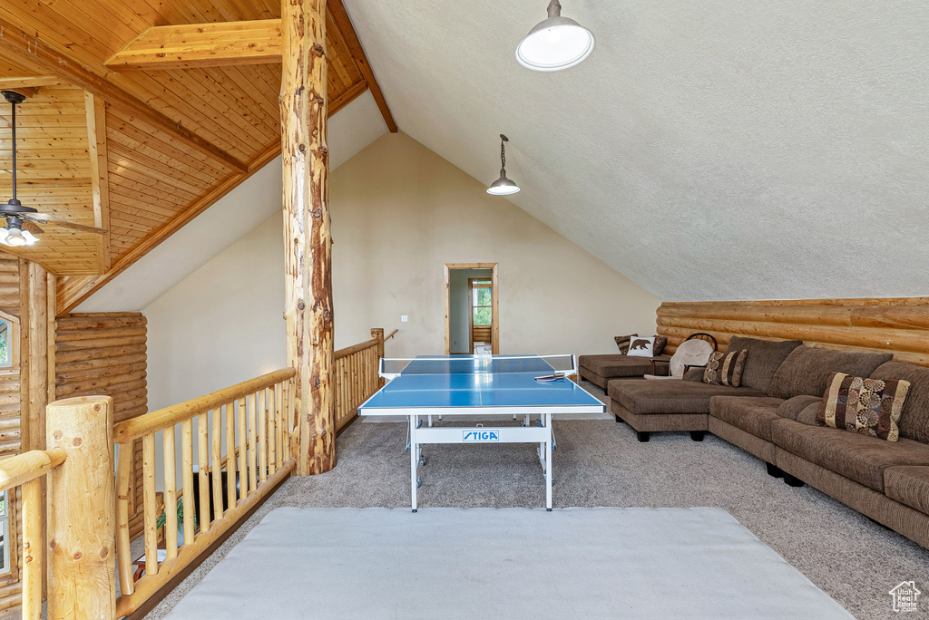 Rec room with rustic walls, carpet floors, a ceiling fan, and wooden ceiling