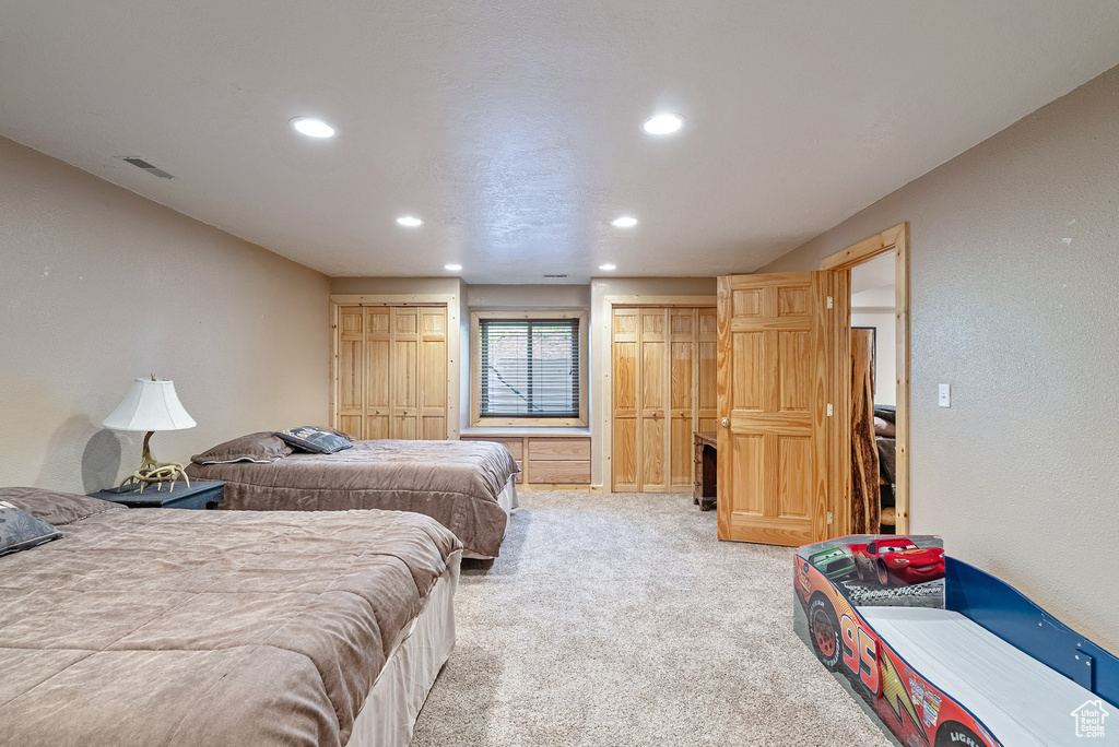 Bedroom featuring two closets, recessed lighting, and light colored carpet