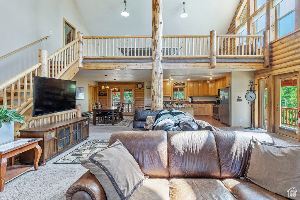 Living room with a towering ceiling, stairs, and light colored carpet