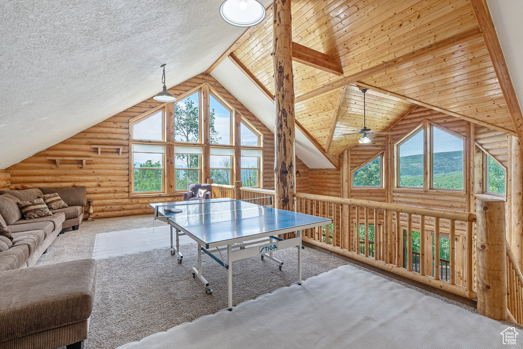 Game room featuring rustic walls, healthy amount of natural light, carpet, and high vaulted ceiling
