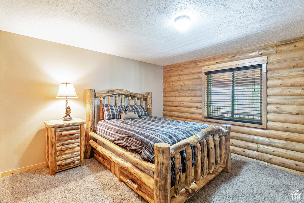 Bedroom featuring light carpet, rustic walls, and a textured ceiling