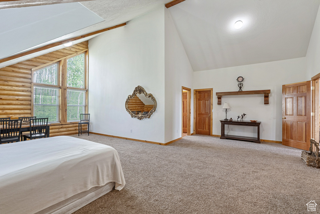 Carpeted bedroom with high vaulted ceiling and rustic walls