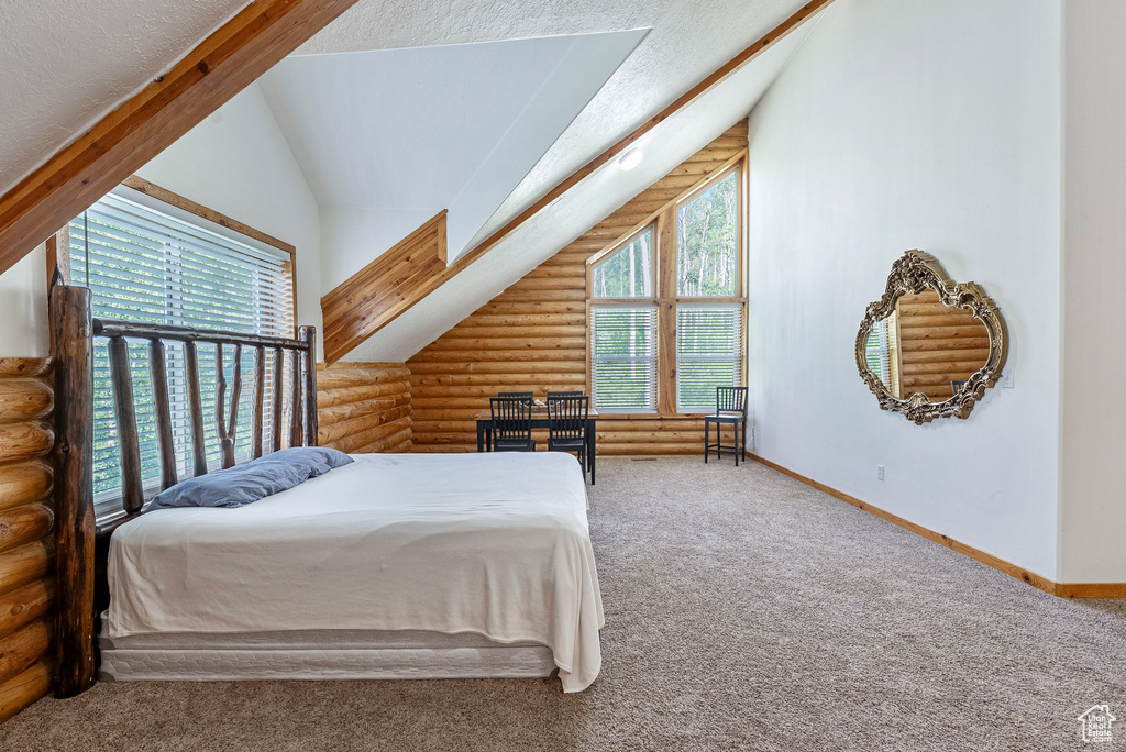 Carpeted bedroom with rustic walls, lofted ceiling, and a textured ceiling