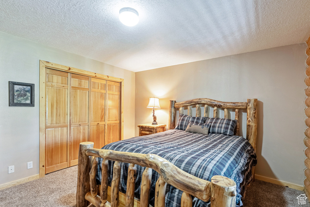 Bedroom featuring carpet flooring, a textured ceiling, and a closet