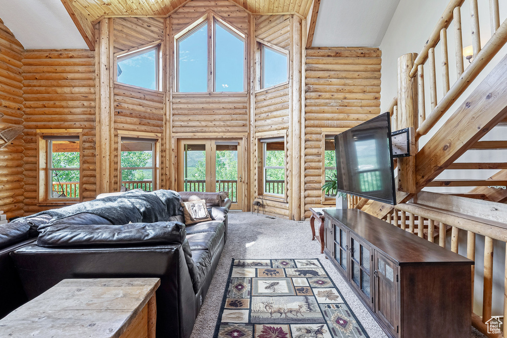 Living room featuring high vaulted ceiling, log walls, french doors, and carpet