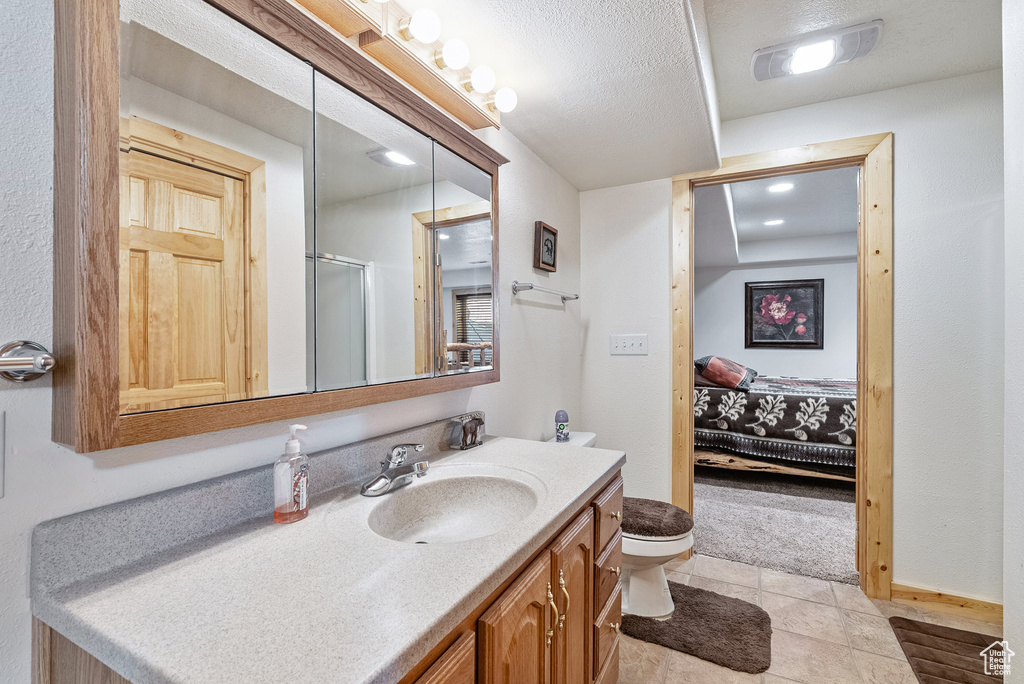 Ensuite bathroom with vanity, a shower with door, and tile patterned floors
