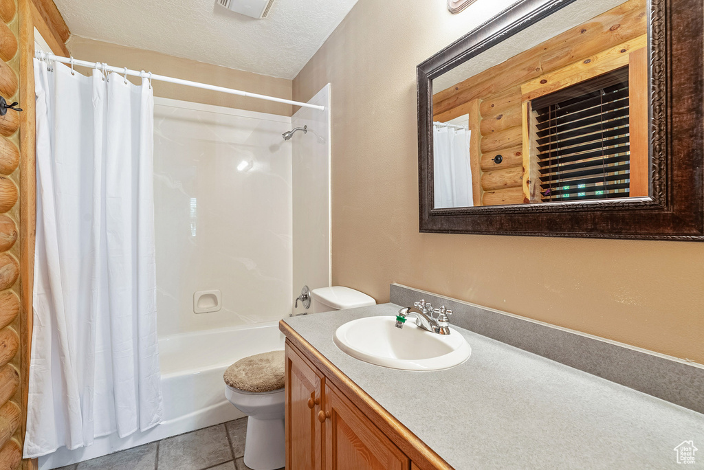 Bathroom featuring log walls, vanity, shower / tub combo with curtain, and tile patterned flooring