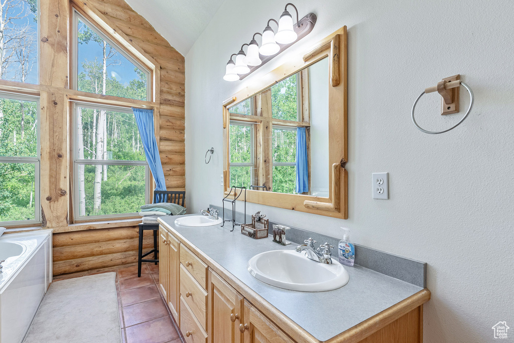 Bathroom with rustic walls, double vanity, lofted ceiling, a tub to relax in, and tile patterned flooring