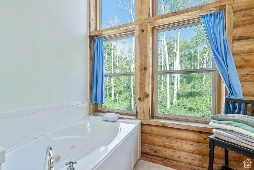 Bathroom featuring rustic walls and a jetted tub