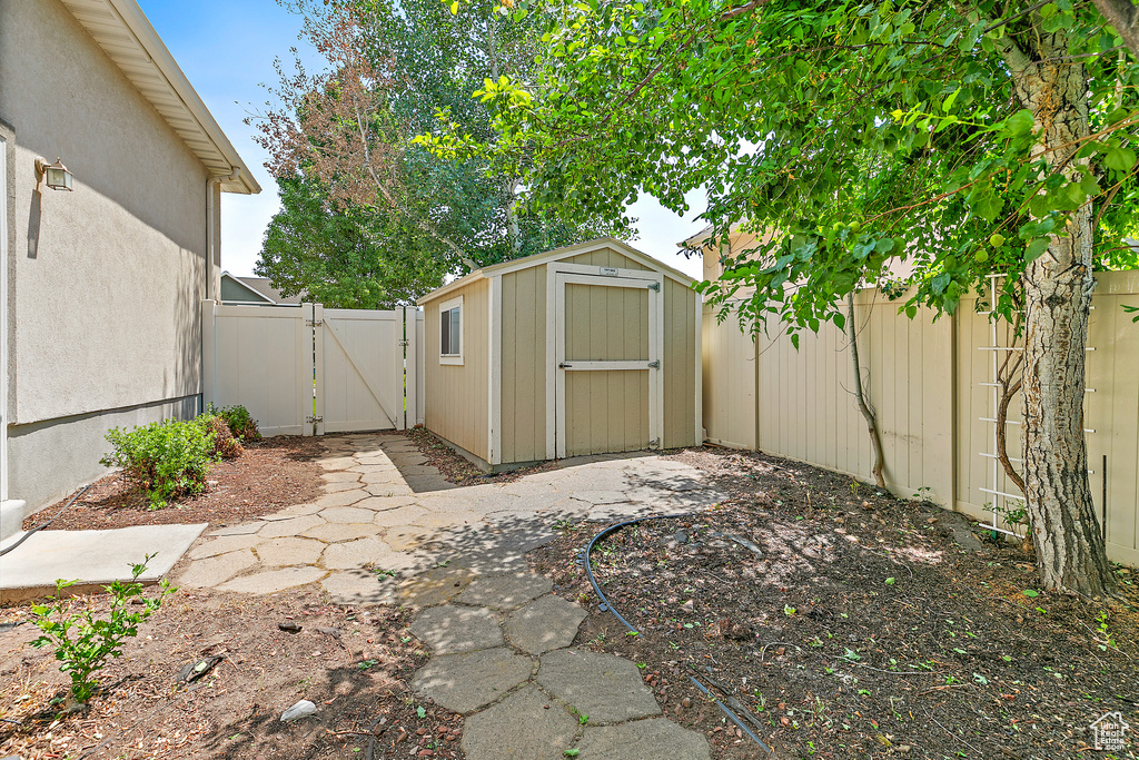 Fenced backyard featuring a gate and a storage unit