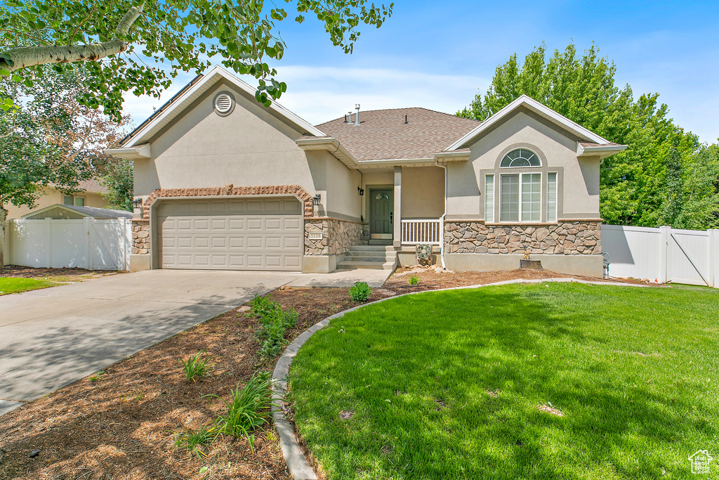 View of front of house featuring stucco siding, a garage, concrete driveway, stone siding, and a gate