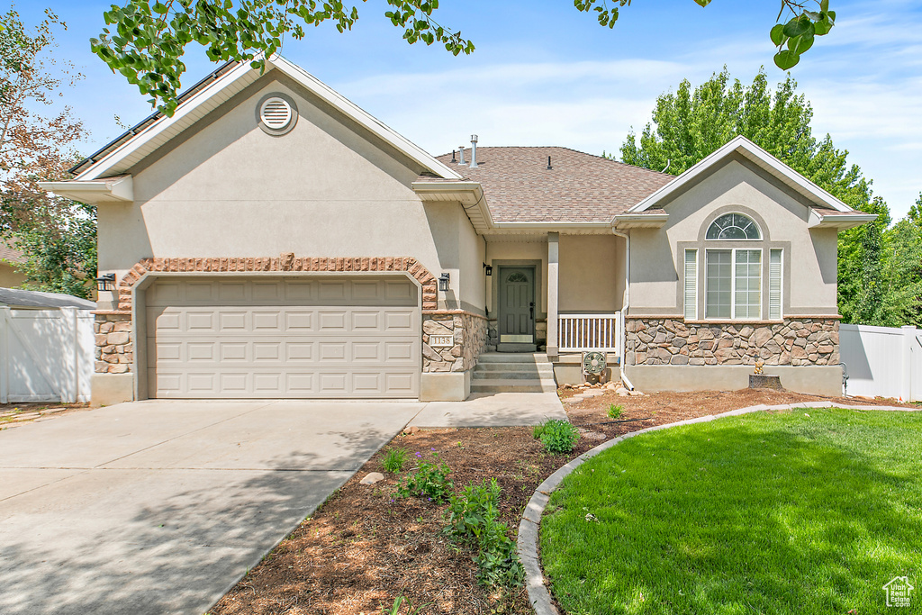 View of front of home with stone siding, stucco siding, an attached garage, concrete driveway, and roof with shingles