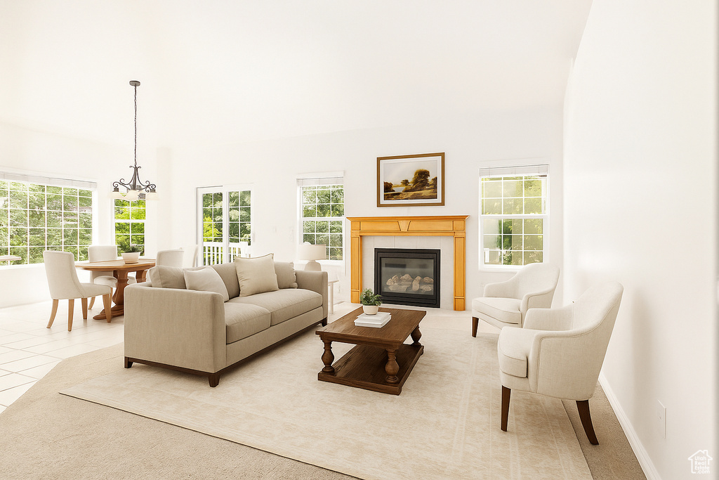 Living room with a high ceiling, a glass covered fireplace, a chandelier, and light tile patterned flooring