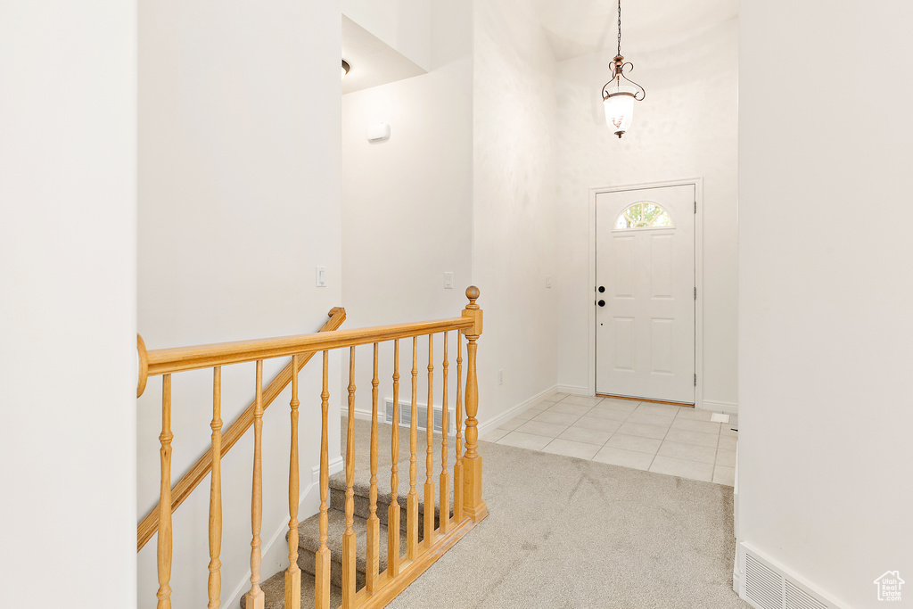 Carpeted entrance foyer with tile patterned floors and a high ceiling