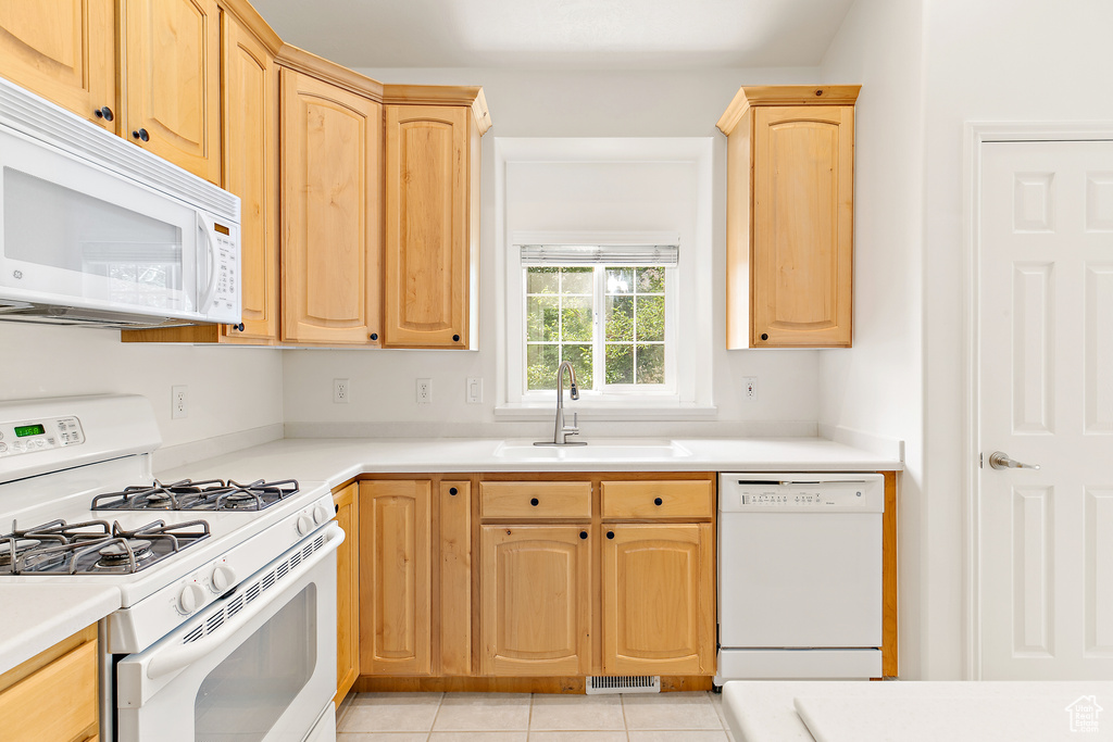 Kitchen featuring white appliances, light brown cabinets, light tile patterned floors, and light countertops