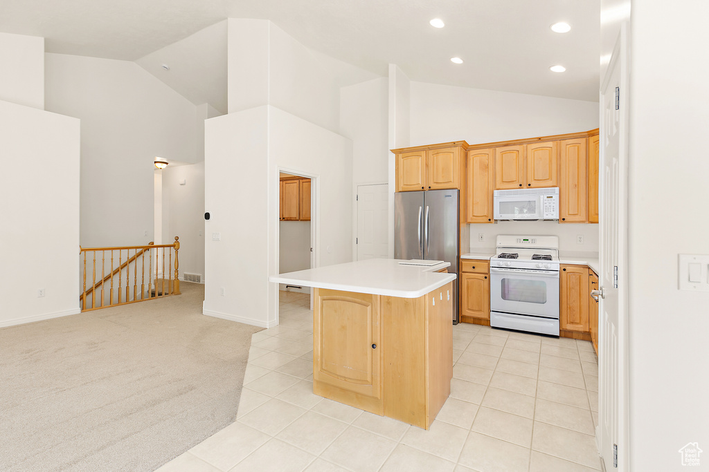 Kitchen featuring white appliances, high vaulted ceiling, a kitchen island, recessed lighting, and light countertops