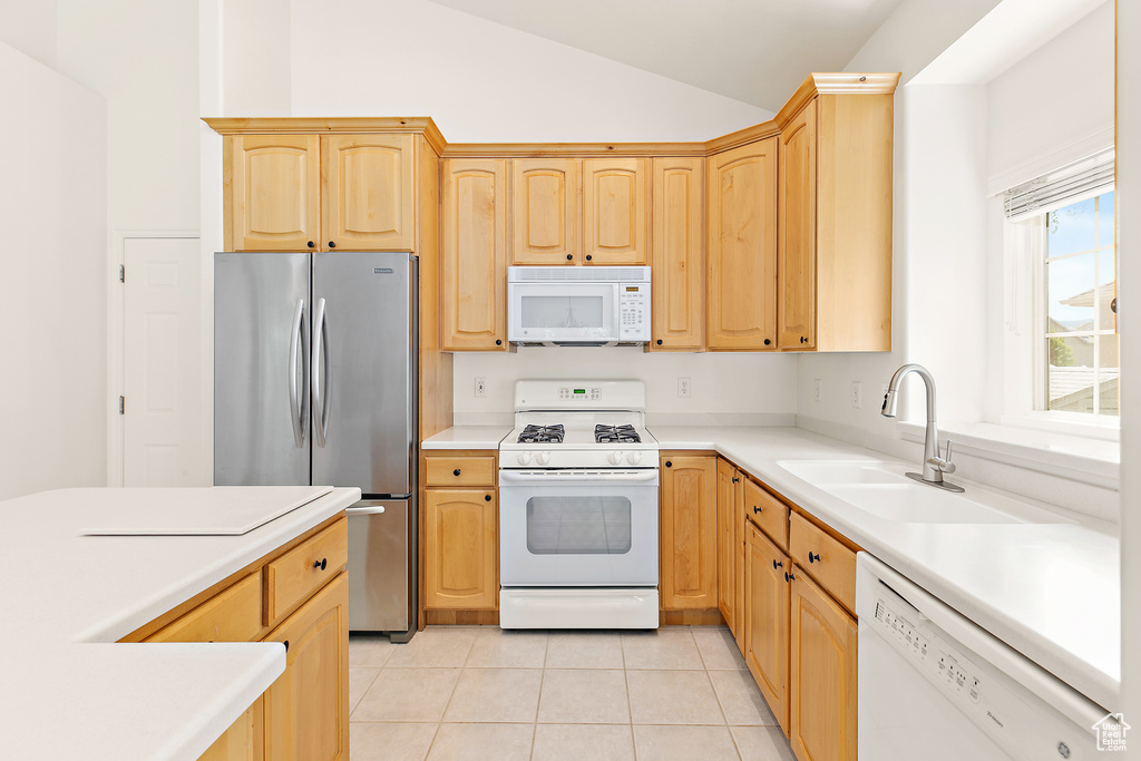 Kitchen featuring white appliances, light brown cabinets, lofted ceiling, light tile patterned floors, and light countertops