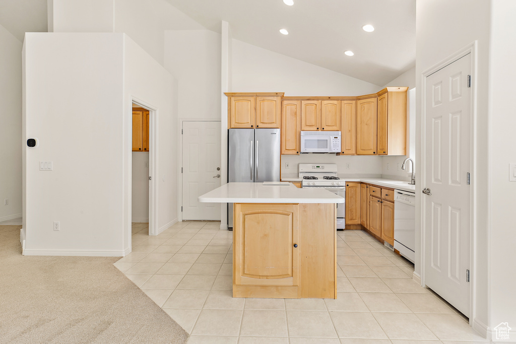 Kitchen with white appliances, a kitchen island, recessed lighting, light countertops, and light brown cabinetry