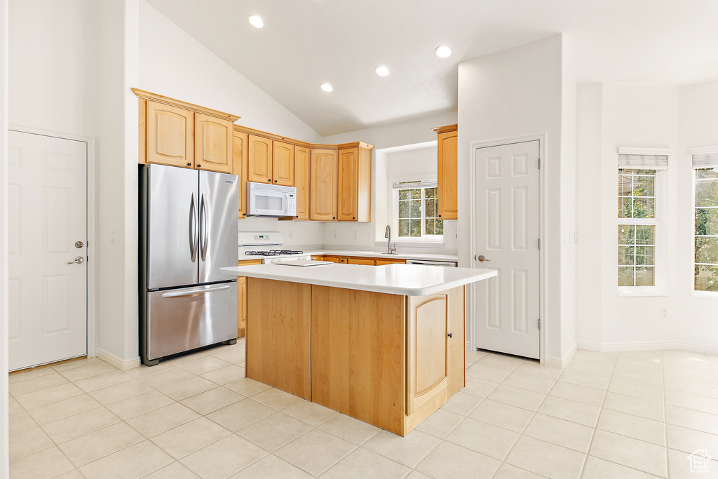 Kitchen with white appliances, a kitchen island, light countertops, recessed lighting, and lofted ceiling