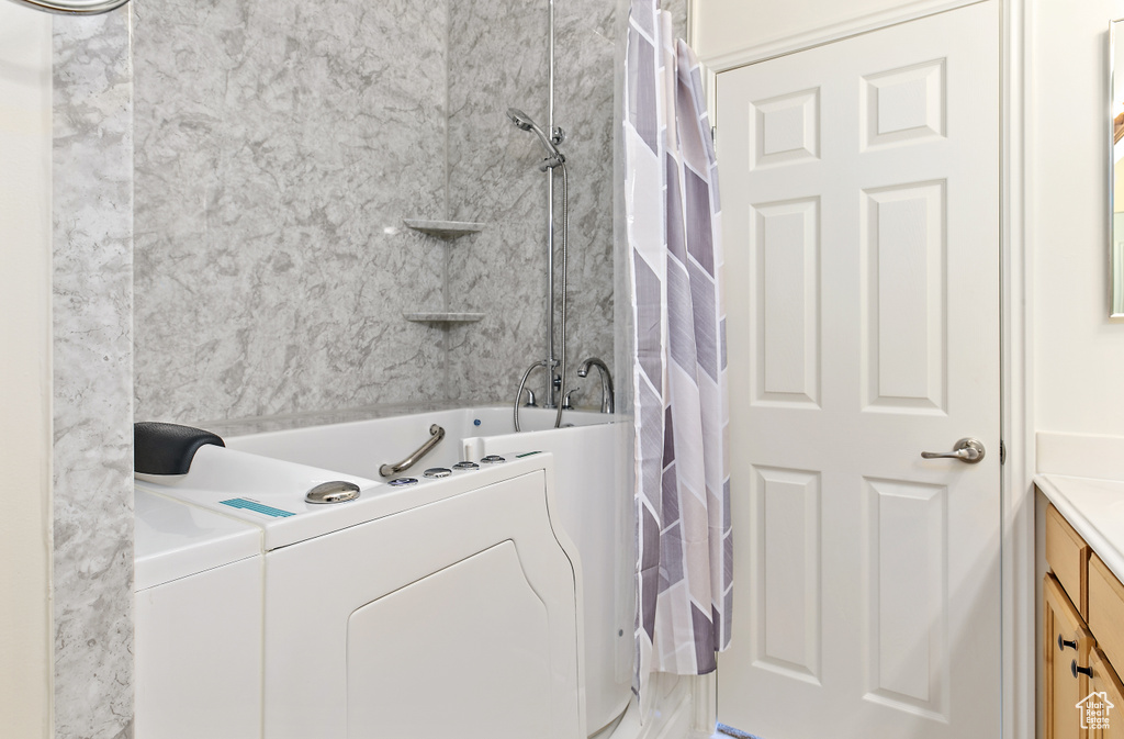 Bathroom featuring washer / dryer, vanity, and shower / bath combo