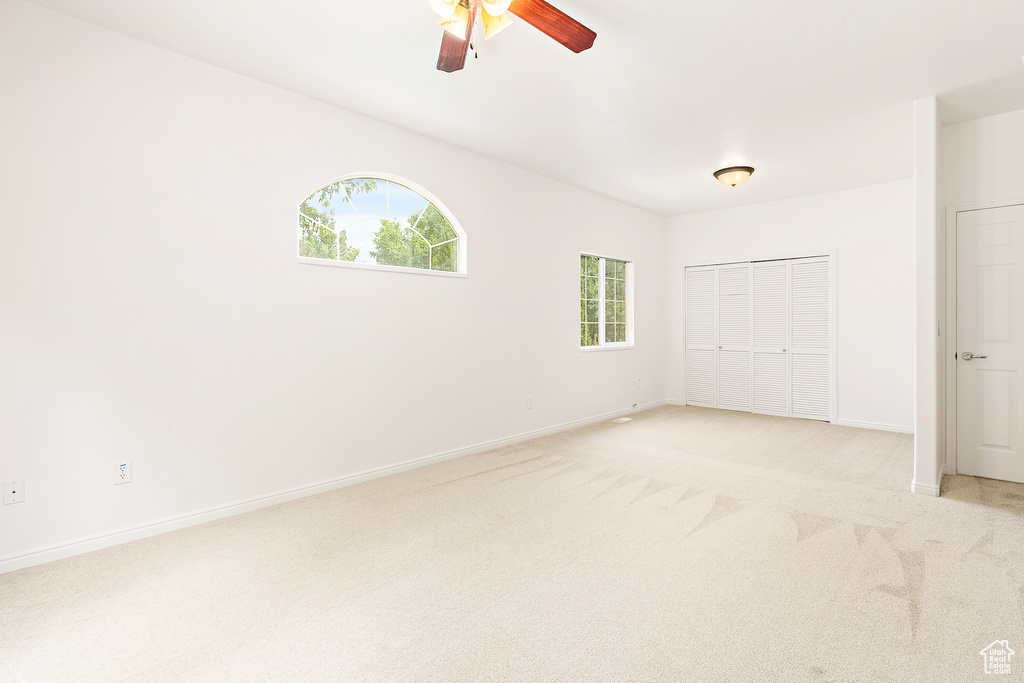 Unfurnished bedroom with light colored carpet, a closet, and ceiling fan