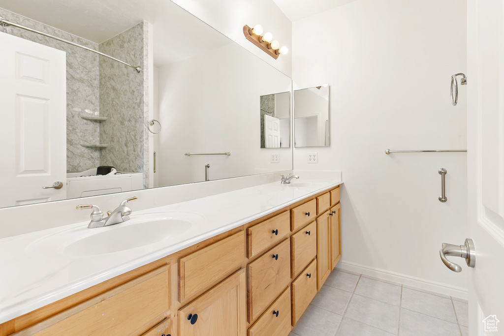 Bathroom with tile patterned floors, double vanity, and shower / bathtub combination