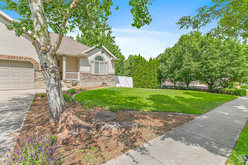 View of home's exterior with stucco siding, stone siding, a yard, a garage, and roof with shingles