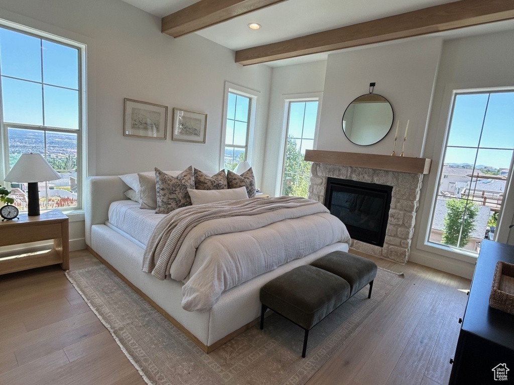 Bedroom with multiple windows, beam ceiling, a fireplace, light wood-type flooring, and recessed lighting