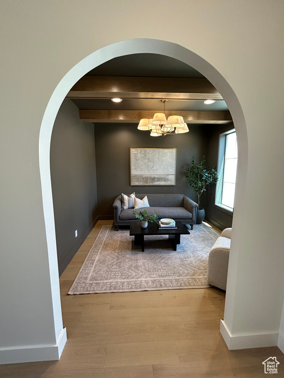 Living room with arched walkways, wood finished floors, a chandelier, and recessed lighting