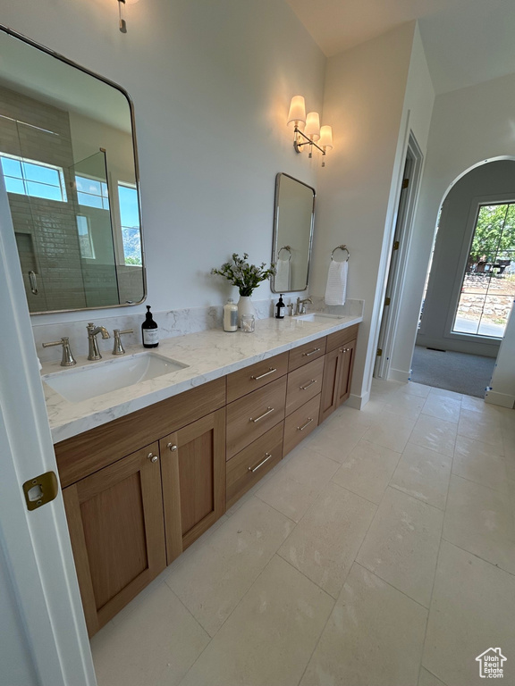 Bathroom featuring double vanity, tile patterned flooring, and a tile shower