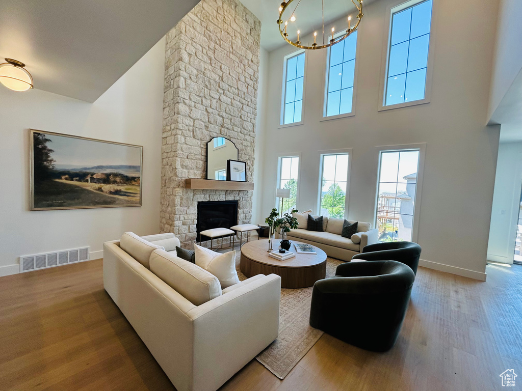 Living area with a chandelier, wood finished floors, a fireplace, and a towering ceiling