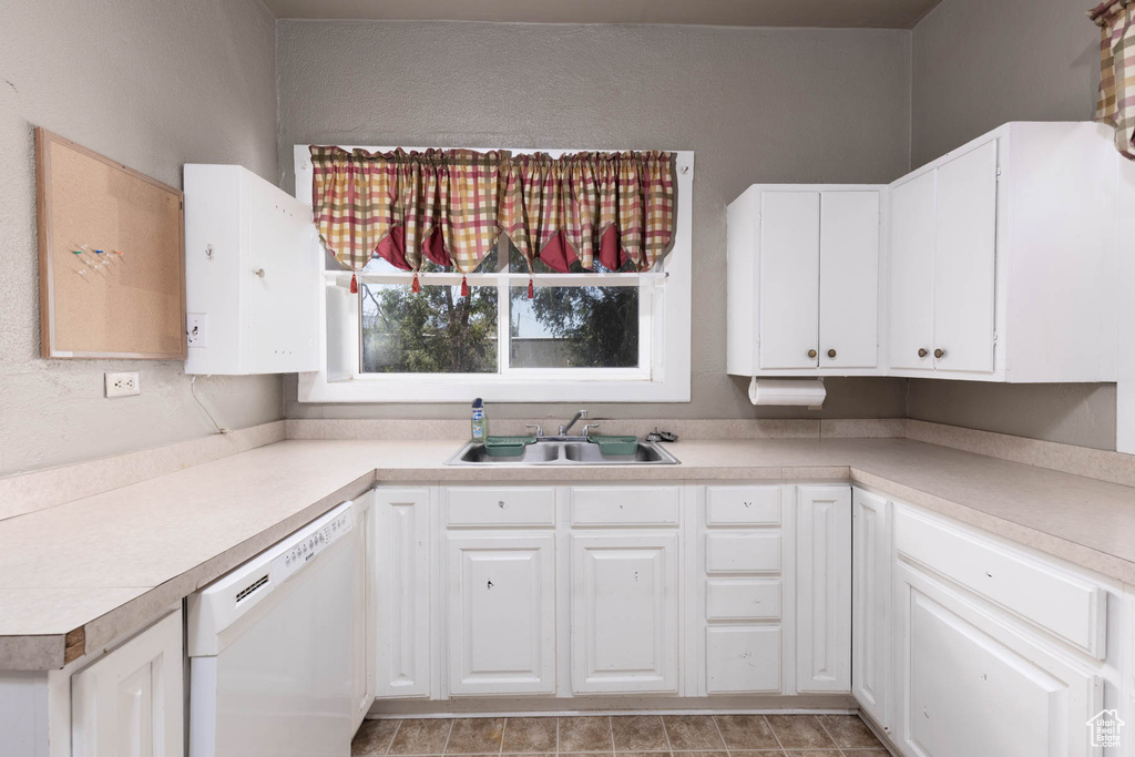 Kitchen with white dishwasher, light countertops, and white cabinetry