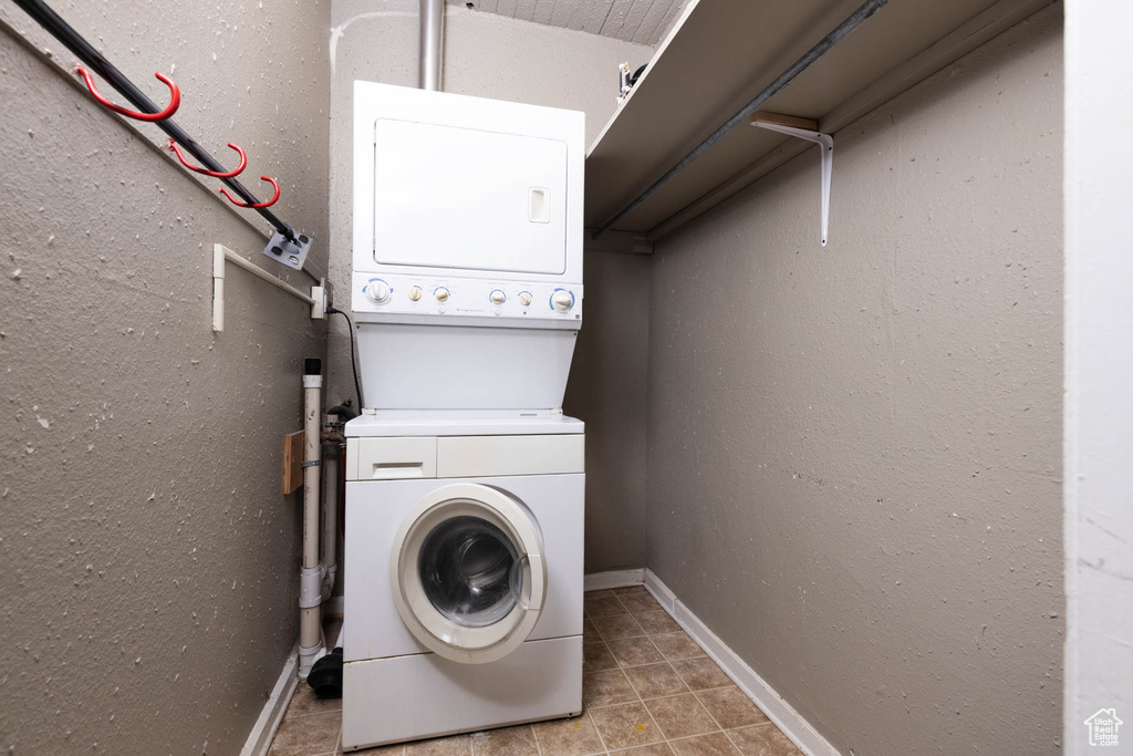 Laundry area with stacked washer and clothes dryer and light tile patterned floors