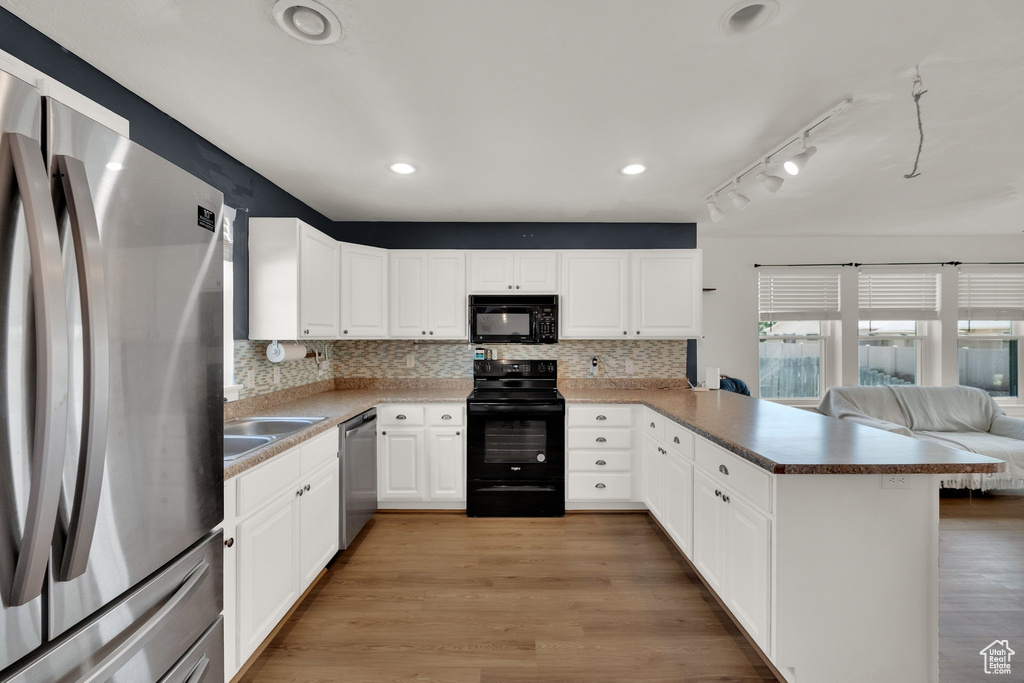 Kitchen featuring black appliances, a peninsula, open floor plan, tasteful backsplash, and recessed lighting