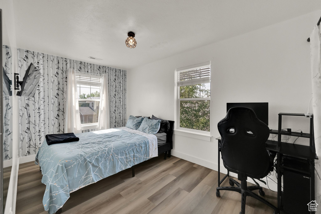 Bedroom with wood finished floors and a desk