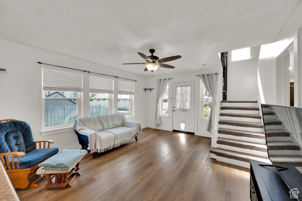 Living room with a ceiling fan, wood finished floors, and stairs