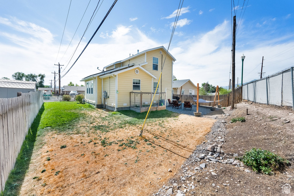Rear view of house with a fenced backyard, a patio area, and a fire pit