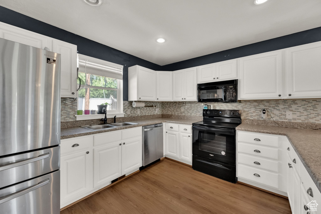 Kitchen featuring black appliances, white cabinetry, and recessed lighting