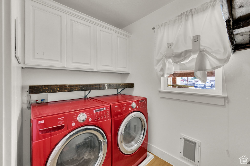 Laundry area featuring cabinet space, separate washer and dryer, and wood finished floors