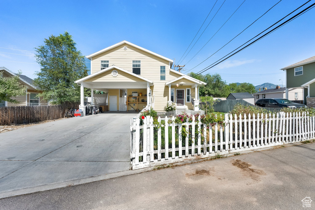 Traditional-style home with concrete driveway, a fenced front yard, and a carport