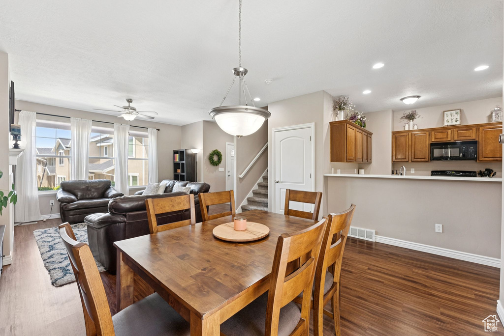 Dining space featuring dark wood-type flooring, recessed lighting, a ceiling fan, and stairs