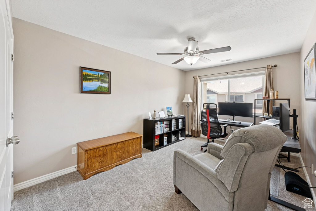 Carpeted living room with a desk and ceiling fan