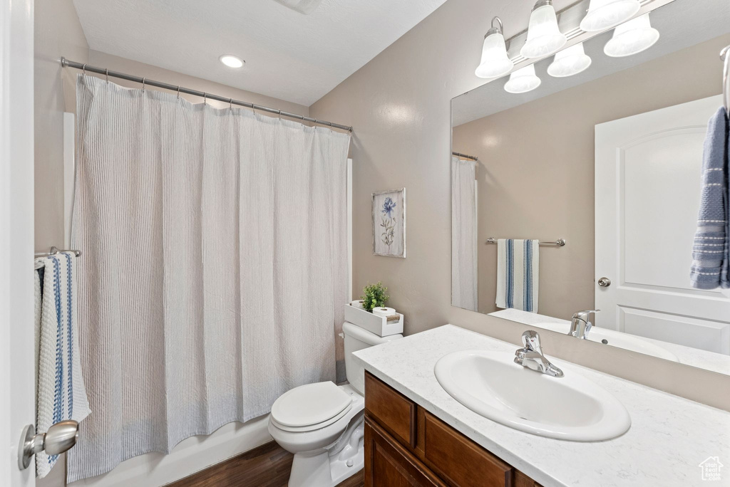 Bathroom with vanity, shower / bath combo with shower curtain, and wood finished floors