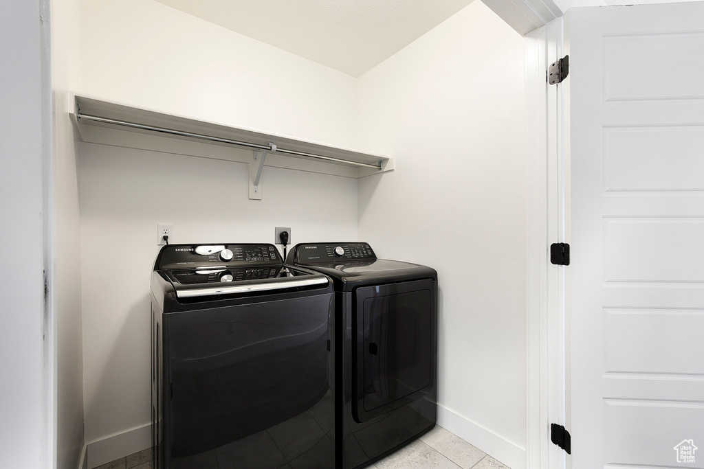Laundry room featuring washer and dryer and light tile patterned flooring