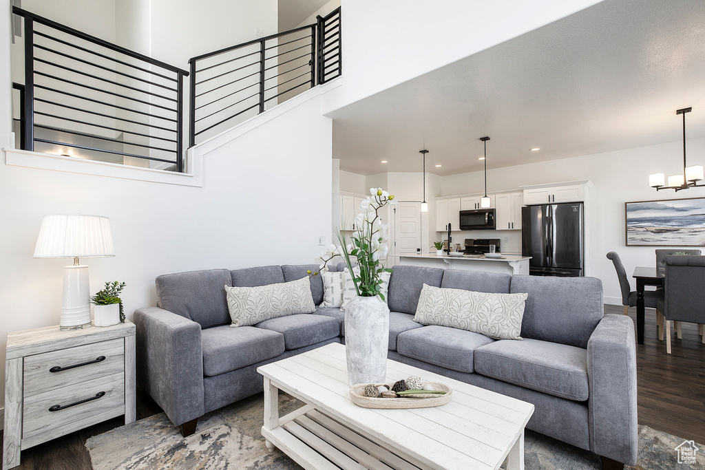 Living area with dark wood finished floors, a chandelier, recessed lighting, a high ceiling, and stairway