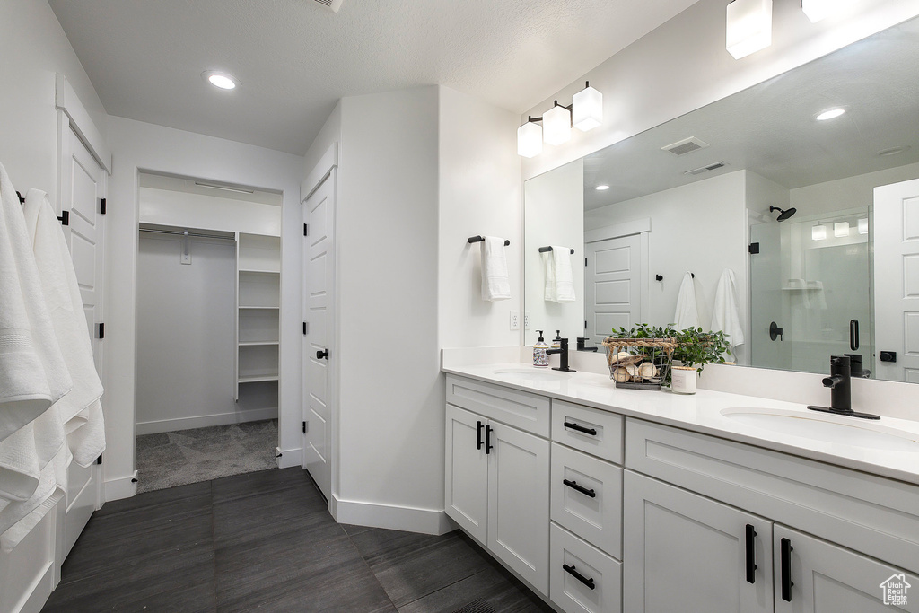 Full bathroom featuring a stall shower, double vanity, a spacious closet, wood finished floors, and recessed lighting