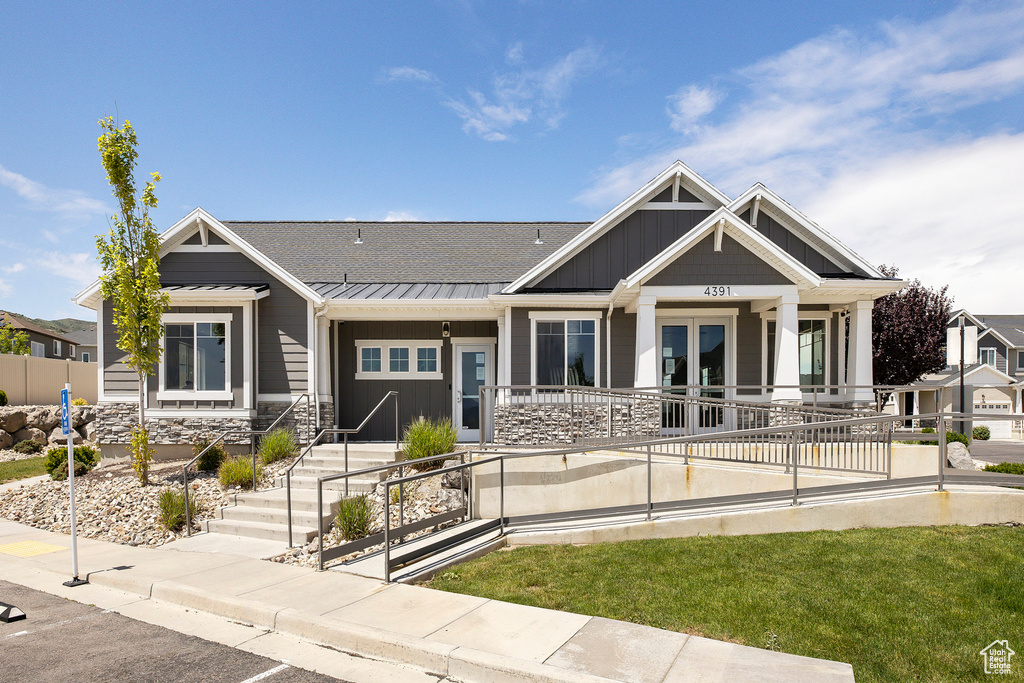 View of front of home with a standing seam roof, stone siding, french doors, a metal roof, and an attached garage