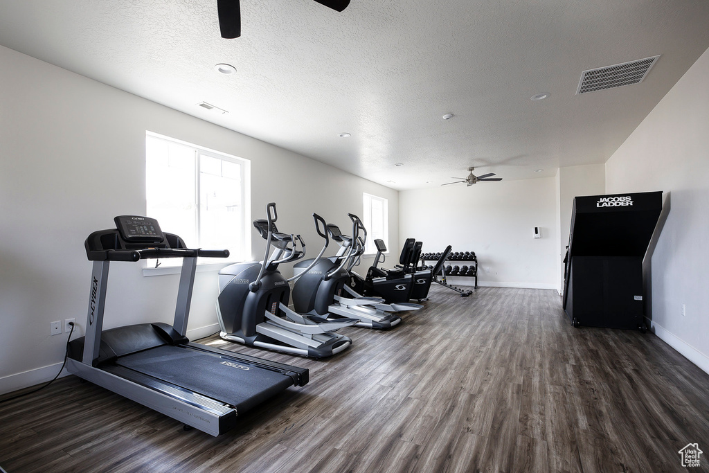 Exercise room featuring ceiling fan, dark wood finished floors, and a textured ceiling