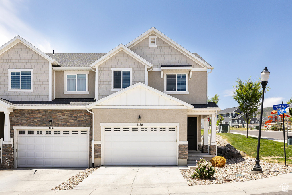 View of front of home featuring stone siding, concrete driveway, a garage, and stucco siding