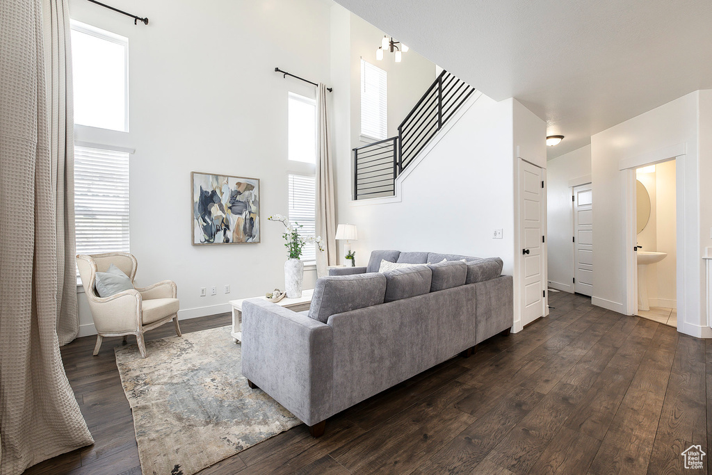 Living area with dark wood finished floors, a high ceiling, and stairway